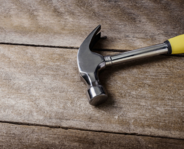 57826370 - single handed worn sledge hammer on grunge wood background